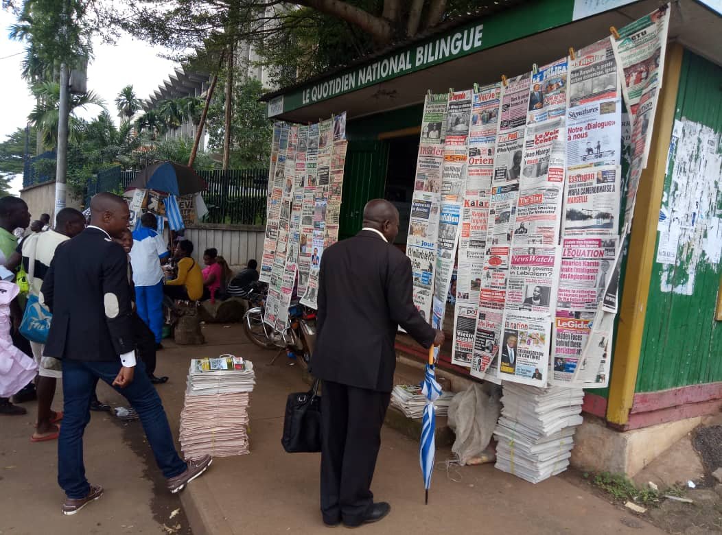 Some Cameroonians reading newspaper front pages at a kiosk adjacent the Ministry of Finance in Yaounde